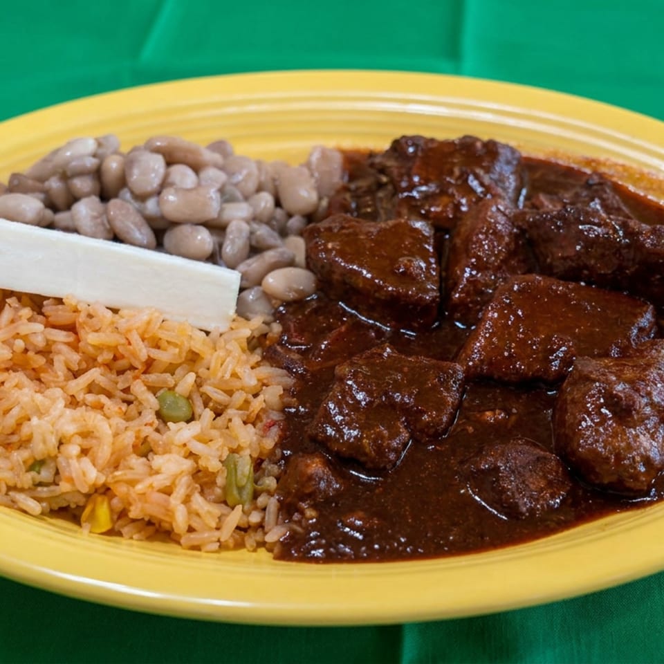 Yellow plate of Mexican-style rice, pinto beans, white cheese, and braised beef in dark sauce on green fabric.